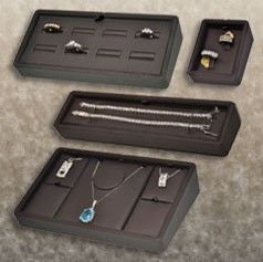 A set of four trays that are holding jewelry.